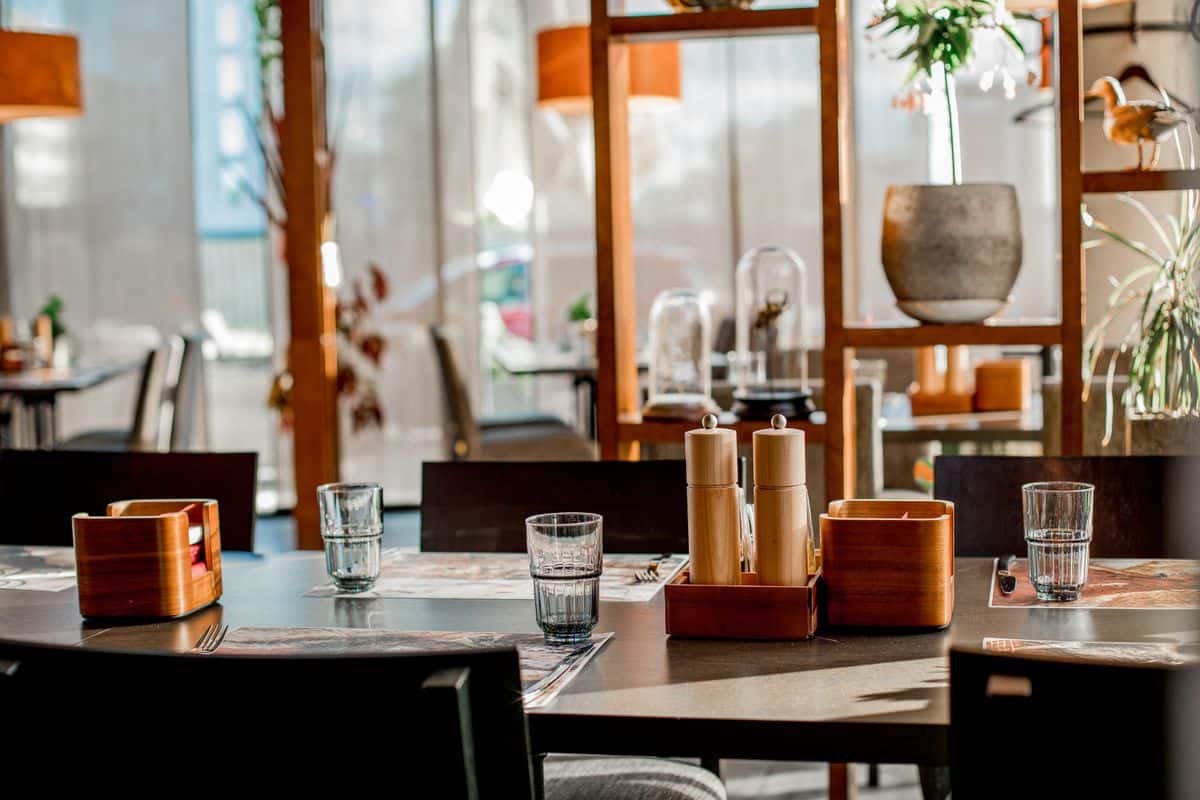 Gün ışığı alan çağdaş bir restoran salonunda servise hazırlanmış masa